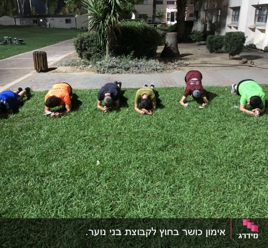 קבוצת אנשים מבצעת תרגיל פלאנק על דשא ירוק.